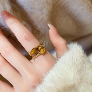 Detailed close-up of gold plated rings featuring oval tiger eye and yellow zircon stones