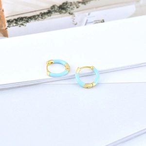 Detail of round gold hoop earrings with light blue enamel coating on white background
