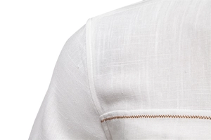 Detailed close-up of white linen shirt shoulder with brown decorative stitching