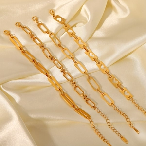 Detail of 18K gold stainless steel chain bracelets with heart motifs on white silk