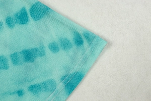 Detailed close-up of high-density knit mesh fabric with blue tie-dye pattern and fine stitching