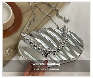Close-up of silver shell-shaped evening bag with pearl bead handle and chain strap