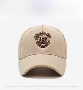 Détail de face d'une casquette beige avec broderie écusson marron et lettre H centrale