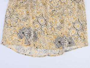 Detail of yellow geometric floral print fabric with vertical stripes and curved hemline