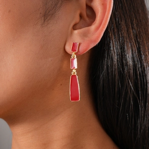 Close-up of red and gold three-tier geometric dangling earrings worn by a model