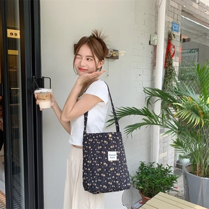 Close-up of navy blue quilted cotton tote with floral pattern and white label detail