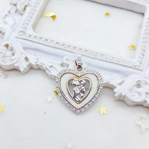 Silver heart pendant with white enamel and mother-child embrace on a vintage background
