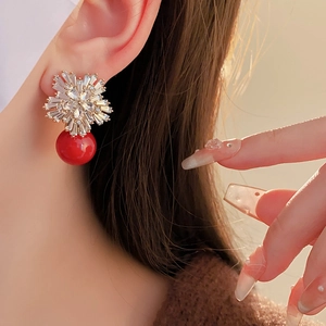 Makroaufnahme luxuriöser Blumen-Perlenohrringe mit Kristallen und roten Perlen am Model