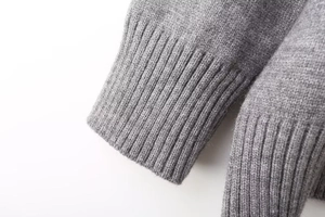 Macro shot of grey knitted sweater showing detailed ribbed cuffs and texture