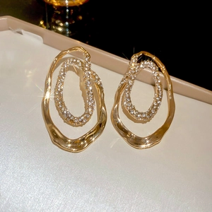 Close-up of irregular 18K gold earrings with sparkling pave-set crystal inner rings