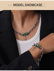 Close-up of titanium steel necklace and bracelet set with green gemstones on model
