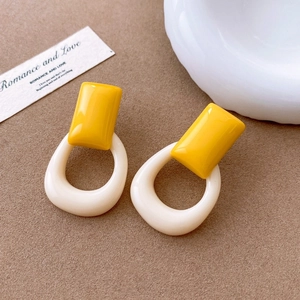 Detail of geometric resin earrings in yellow and cream white with retro French style