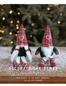 Close-up of plush Christmas gnomes with plaid hats on a snowy wooden stand