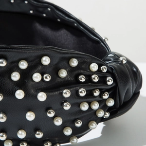 Detail of black pebbled leather headband featuring white pearls and silver metal studs