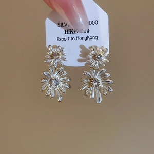 Close-up of double-layered daisy earrings with white enamel and zircon stones