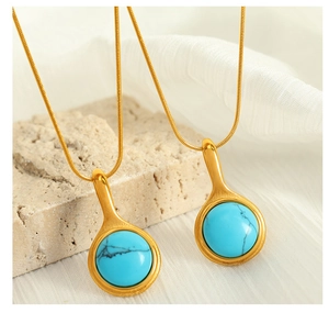 Detail view of retro turquoise pendants on golden snake chains against natural stone