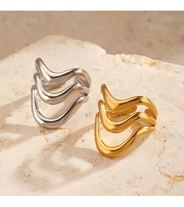 Detail of minimalist wavy layered open rings in gold and silver finish on stone