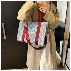 Detail of light blue denim tote bag with red stripes and gold hardware accessories