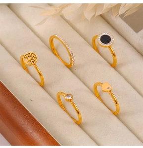 Detailed view of five gold-plated stainless steel rings with tree of life and heart motifs