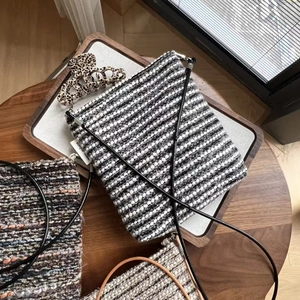 Detail of woven striped crossbody bags with rope straps on a rustic wooden table
