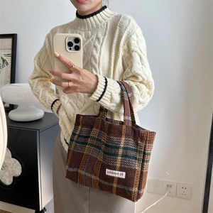 Detail of brown plaid tweed tote bag with logo patch and textured wool finish
