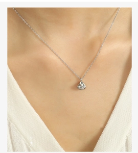 Close-up of minimalist silver teardrop pendant necklace worn on neck with metallic shine