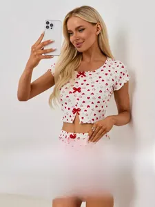 Dettaglio del pigiama bianco con stampa a cuori e fiocco decorativo in nastro rosso