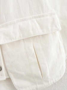 Close-up of a white denim vest showing pocket flap detail and high-quality stitching
