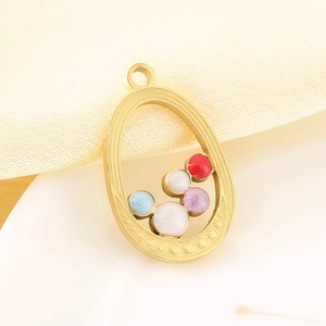 Detail of 18K gold-plated oval pendant featuring colorful enamel beads on fabric