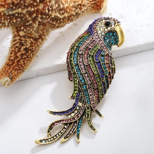 Detailed macro view of a gold parrot brooch with colorful rhinestones on a white surface