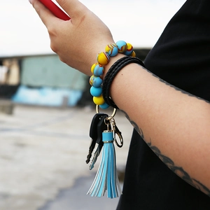 Wristlet keychain with colorful silicone beads and blue tassel worn on a wrist