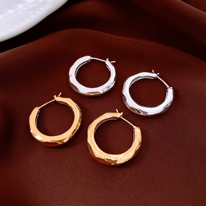 Detailed macro view of gold and silver hoop earrings with hammered texture on silk fabric
