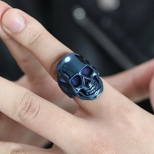 Dettaglio dell'anello a teschio in acciaio lucido con sfumatura blu su dito maschile