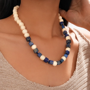 Détail d'un collier bohème avec perles crème et accents bleu foncé portés par un mannequin