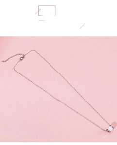 Detail van de zilveren ketting met witte keramische cilindrische hanger op roze achtergrond