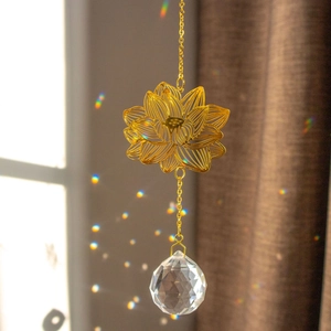 Golden lotus suncatcher with crystal prism reflecting rainbow light in a sunny window