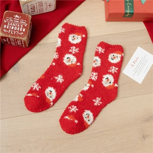 Detailed close-up of thick red coral fleece Christmas socks with festive Santa patterns