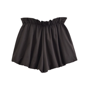 Détail d'un short plissé noir à taille haute avec une ceinture élastique sur fond blanc