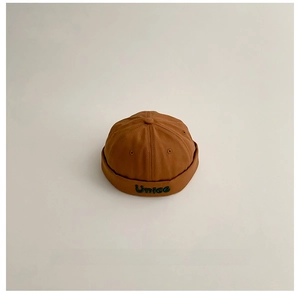 Dettaglio del berretto docker marrone caramello con ricamo Unice verde di alta qualità