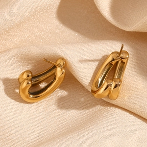 Macro shot of 18K gold-plated double-layer U-shaped earrings on beige silk fabric