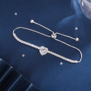 Macro shot of silver heart zircon bracelet with adjustable slider clasp on blue silk