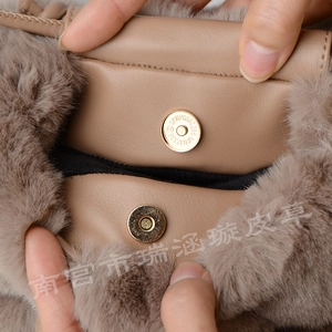Detail view of the khaki faux rabbit fur bag featuring a magnetic gold clasp and leather trim