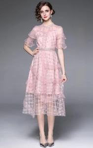 Détails de robe féerique rose avec broderie dorée et perles scintillantes au décolleté