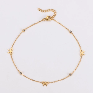 Detailed close-up of golden stainless steel anklet with bow charms and zircon stones