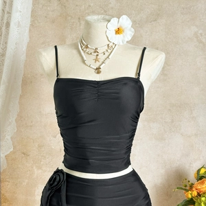 Detail of black bikini top with pleats and 3D rose flower decoration on the side of the bottom