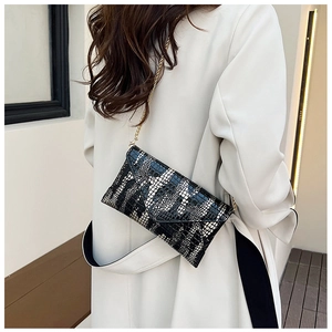 Detail of a black and white faux snake skin envelope bag with elegant gold chain strap