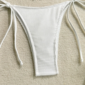 Detailed macro view of white bikini bottoms featuring a honeycomb waffle texture and side ties