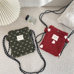 Plush heart pattern crossbody bags in green and red with checkered strap on rug