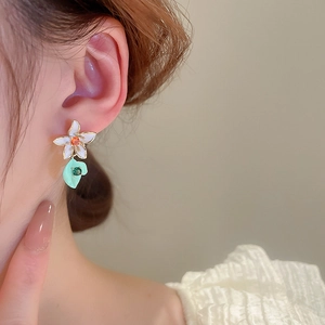 Asymmetric floral bow earrings with colorful enamel petals and gold plating on model