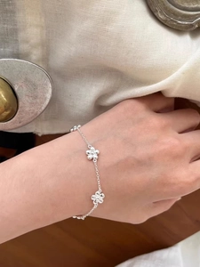 Close-up of a s925 silver flower bracelet worn on a wrist over a rustic wooden table
